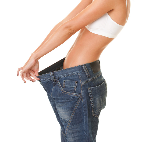 Mujer muestra su pérdida de peso mediante el uso de un viejo jeans, aislado en
 - Foto, Imagen