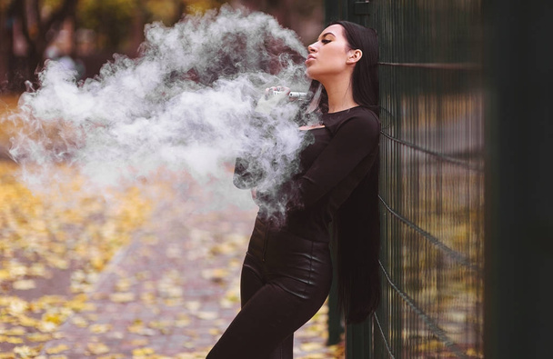 Brunette sexy woman vaping outdoors. - Photo, Image