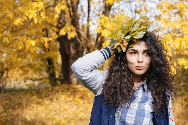 Kaunis malli poseeraa syksyllä puistossa nippu lehtiä
 - Valokuva, kuva