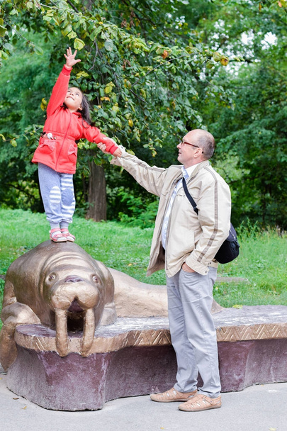 Щасливий дідусь і маленька онучка грають у зоопарку
.  - Фото, зображення