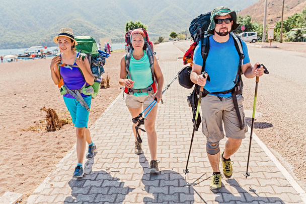 группа молодых счастливых друзей-студентов, путешествующих по ликийской тропе с рюкзаками на прибрежной дороге в лесу. Пешие прогулки и треккинг в Турции
 - Фото, изображение