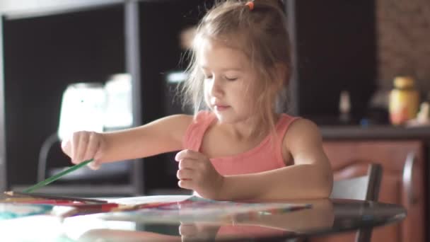 kind van 6 jaar tekent huizen zitten aan een tafel. klein meisje in de ochtendzon - Video