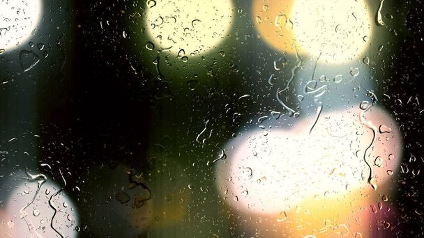 Капли дождя стекают по стеклу на боком фоне движущихся автомобилей
 - Фото, изображение