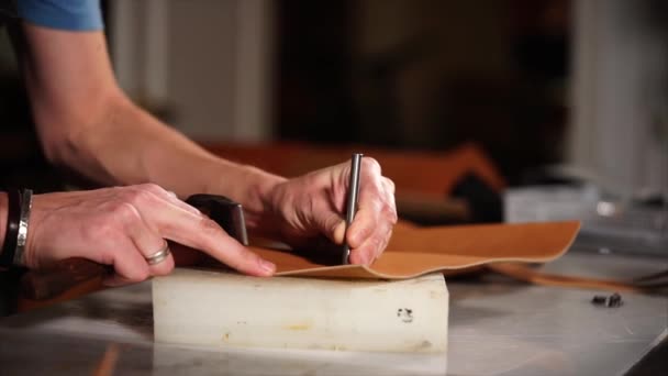 primer plano de un empleado manos, que hace agujeros con un martillo en una pluma
 - Metraje, vídeo