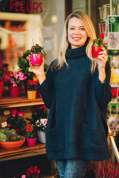 Mujer feliz eligiendo pequeños regalos en la tienda de flores, usando jersey azul oscuro cálido
 - Foto, imagen