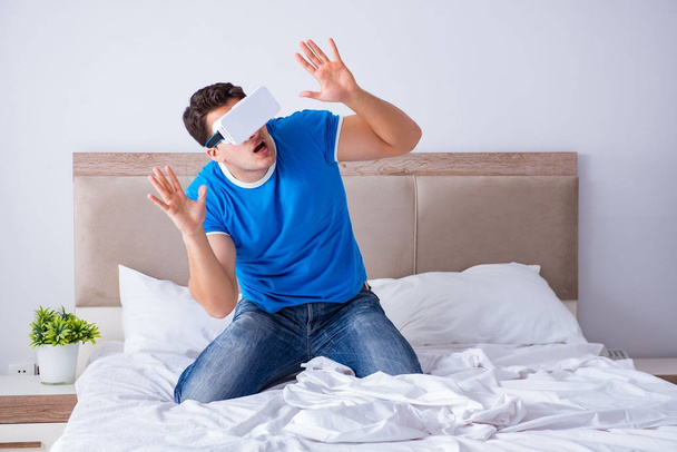 Молодий чоловік у ліжку в наборі голови віртуальної реальності vr
 - Фото, зображення