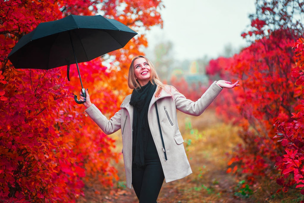 Onnellinen nainen, jolla on sateenvarjo. Nainen yllään harmaa takki syksyllä
 - Valokuva, kuva