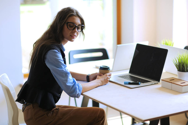 Young woman sitting at office table with laptop. Young woman. Laptop - Foto, imagen