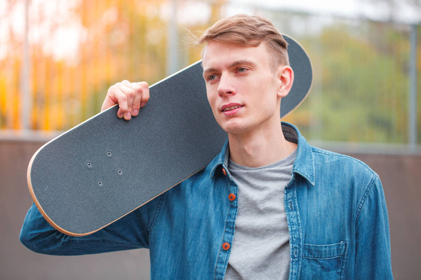 Young skatebarder posing with skateboard in the skatepark. Sport concept. - Photo, Image