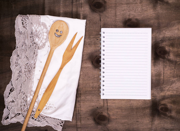 bloco de notas aberto em uma linha e uma colher de madeira com um garfo
 - Foto, Imagem