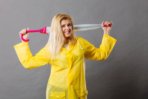 Happy woman wearing raincoat holding closed umbrella - Foto, afbeelding