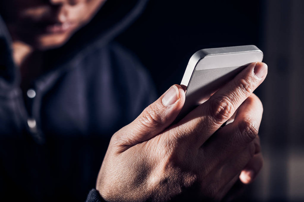 З капюшоном кіберзлочинний хакер, використовуючи мобільний телефон Інтернет злому в
 - Фото, зображення