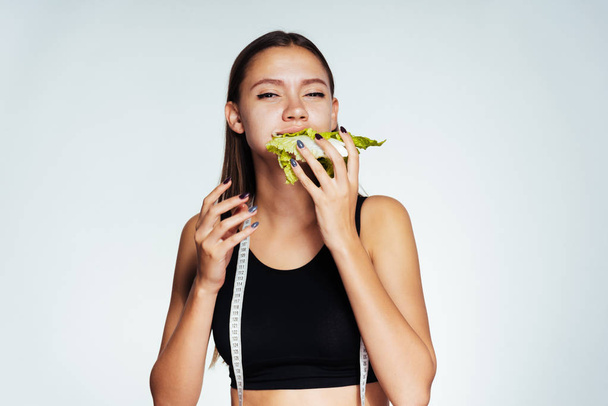 a young athletic girl in a black top keeps track of her weight, eats a useful Peking cabbage - Foto, Imagen