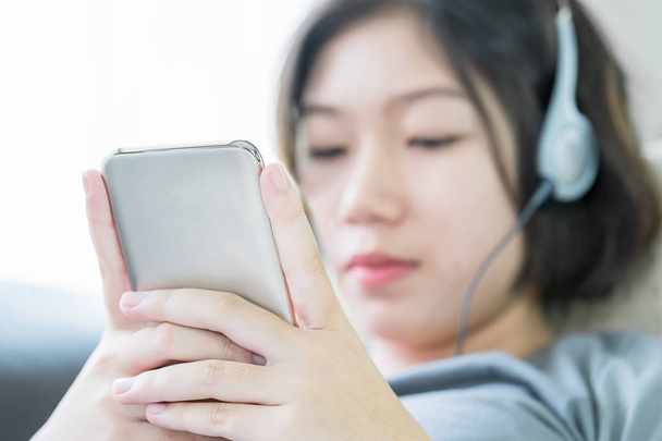 Asian woman listening music from mobile phone - 写真・画像