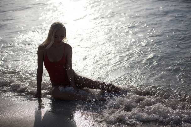 sexy girl lies in a red bathing suit near the ocean. - Fotó, kép