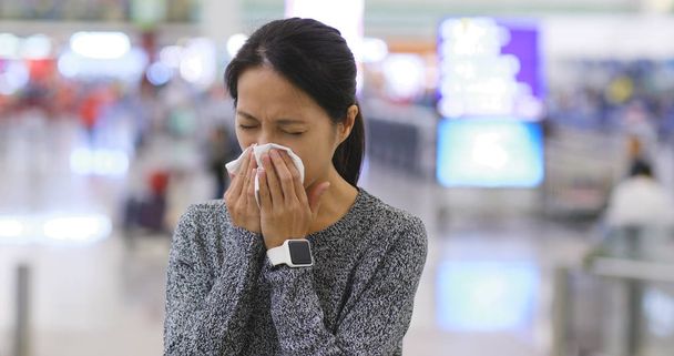 Frau niest am Flughafen von Hongkong - Foto, Bild