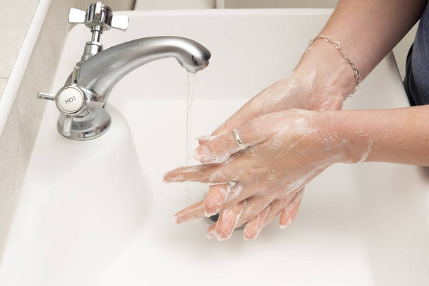 Lavaggio a mano corretto sul lavandino con acqua che scorre dal rubinetto
 - Foto, immagini