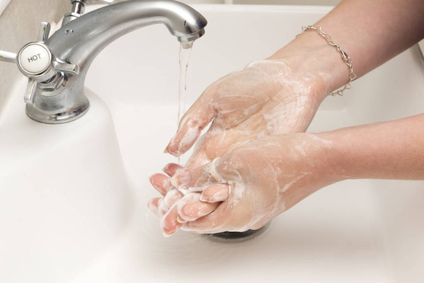 Миття рук на раковині для ванної з водою, що тече від крана
 - Фото, зображення