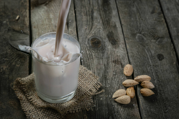 Pouring almon milk on rustic wood background - Foto, imagen
