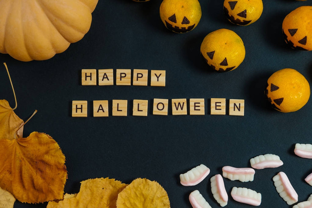 Happy Halloween with fake pumpkins and tangerines with painted s - Фото, изображение