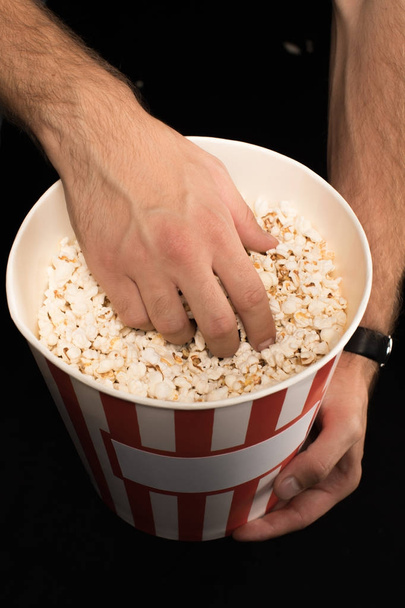 man neemt popcorn uit emmer - Foto, afbeelding