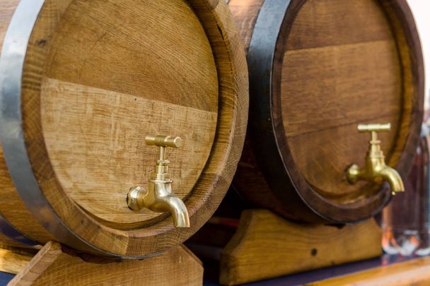 Ξύλινα βαρέλια για κρασί με ένα πάτημα από κίτρινο μέταλλο.  - Φωτογραφία, εικόνα