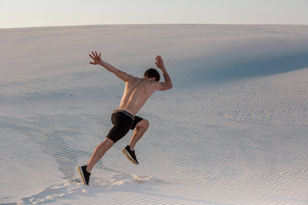 Fit man running fast on the sand. Powerful runner training outdoor on summer. - Photo, image