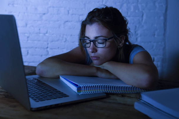 fiatal gyönyörű és fáradt diák lány alszik, hogy a nap, feküdt otthon laptop számítógép asztal kimerült, és kárba a kiadások este tanul  - Fotó, kép