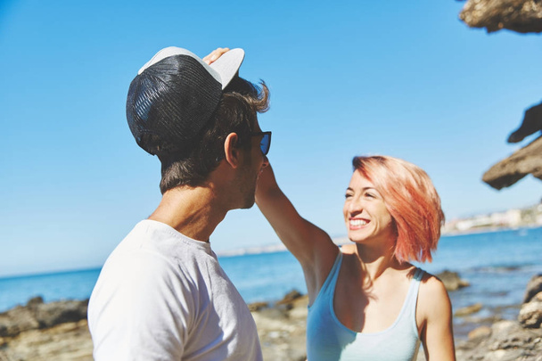 Happy woman taking her boyfriend cap on beach - Foto, Imagem