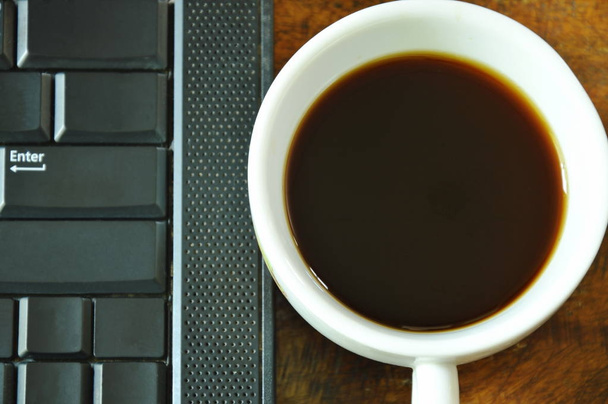  počítač notebook a šálek černé kávy na stole - Fotografie, Obrázek