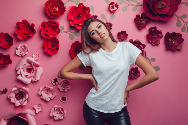 Sexy woman in a white t-shirt on a pink background with flowers. - Fotografie, Obrázek