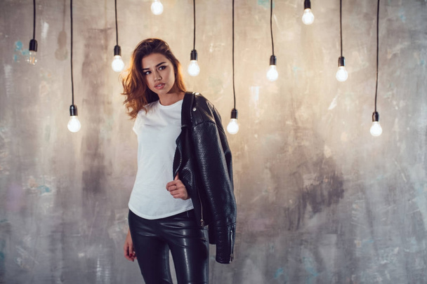 Sexy woman in white t-shirt and jacket on the gray background with lamps. Mock-up. - Фото, изображение