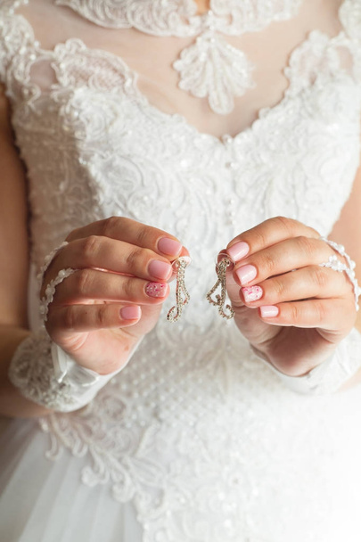 beautiful stylish earrings in the hands of the bride - Fotó, kép