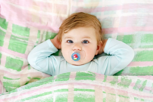 entzückendes kleines Mädchen nach dem Schlafen im Bett. ruhiges friedliches Kind mit Schnuller oder Schnuller - Foto, Bild