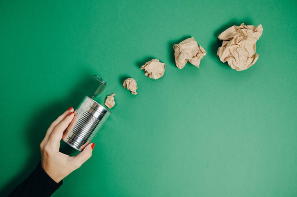Woman Hands with Aluminum jar and crumpled paper on a green back - Foto, imagen