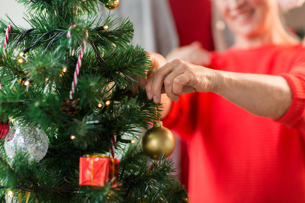 close up of senior woman decorating christmas tree - Foto, imagen