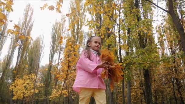 面白い、陽気なかわいい女の子は黄色秋落ち葉のスローモーションを投げてジャンプします。 - 映像、動画