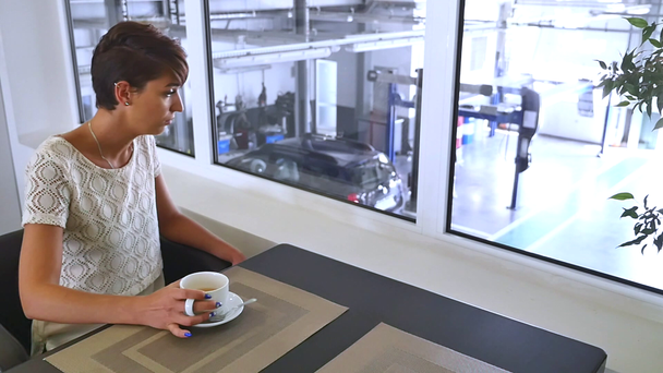 a young, beautiful woman drinking coffee at the Tire fitting - Záběry, video