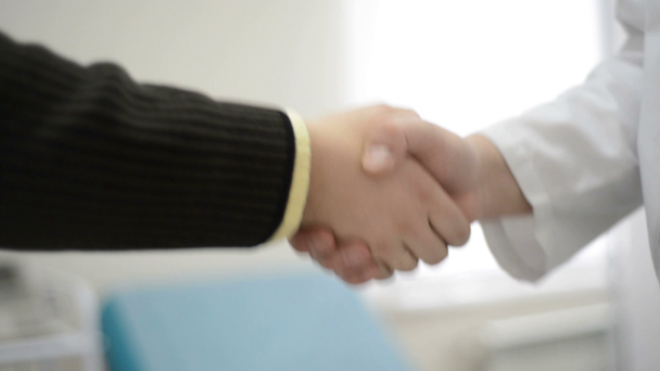 修飾された医師と感謝の患者は握手します。ハンドシェイクは、クリニックでの医療サービス. - 映像、動画