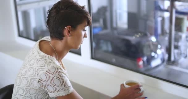 a young, beautiful woman drinking coffee at the Tire fitting - Záběry, video