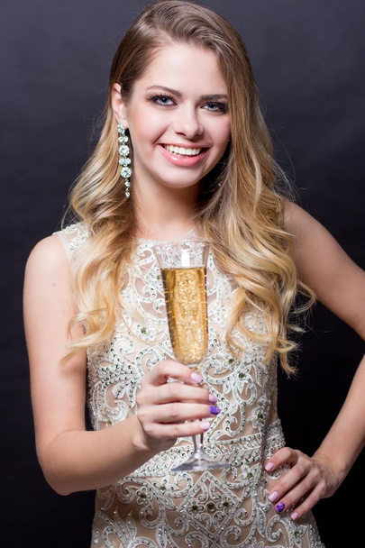 Portrait of a beautiful young woman with a glass of champagne. A party. Celebration. Christmas, New Year, Birthday. Happy woman - Фото, изображение