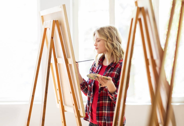 student girl with easel painting at art school - Foto, Imagen