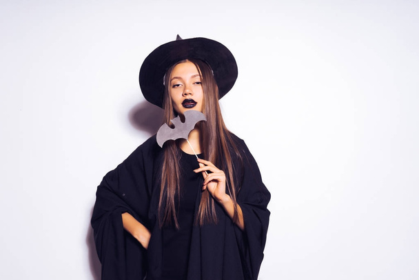 beautiful sexy girl dressed in a witch for Halloween, holding a bat drawing and looking confident - Fotoğraf, Görsel