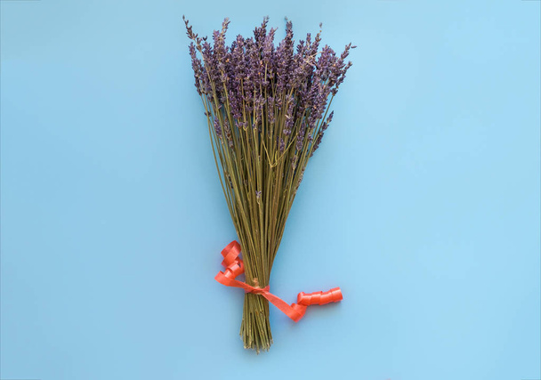 A bouquet of dry lavender in kraft paper on a blue background, symbolizing summer and France. Flat lay, top view. - Foto, Imagen