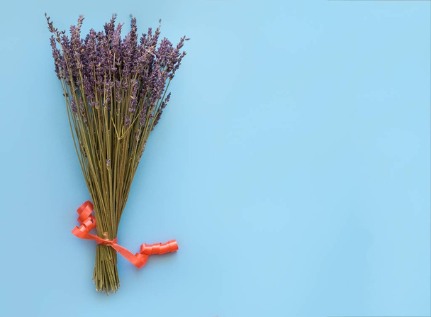 A bouquet of dry lavender in kraft paper on a blue background, symbolizing summer and France. Flat lay, top view. - Foto, afbeelding