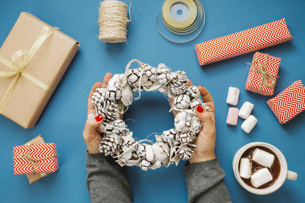 Woman hands holding wreath, hot cocoa with marshmallows, gifts,  - Valokuva, kuva