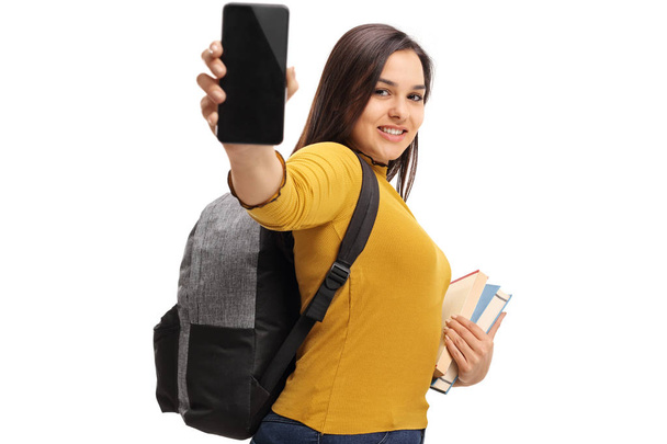 student with a backpack and books showing a phone - Фото, зображення
