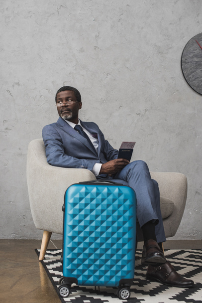 businessman sitting in armchair with passport and ticket - Foto, Imagen