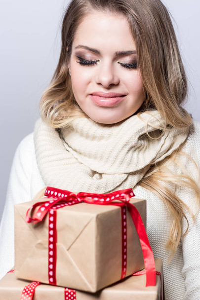 若くてきれいな女性の持株のギフト。幸せな女の子は、白い背景の上の贈り物を保持しています。新しい年。クリスマス。誕生日. - 写真・画像