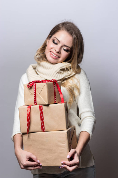 Νεαρή όμορφη γυναίκα εκμετάλλευση δώρα. Ευτυχισμένος κορίτσι κρατώντας δώρα σε άσπρο φόντο. Το νέο έτος. Χριστούγεννα. Γενέθλια. - Φωτογραφία, εικόνα